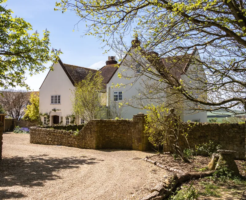 Tapnell Manor at Tapnell Farm, a white country house behind a stone wall with a gravel drive and spring trees