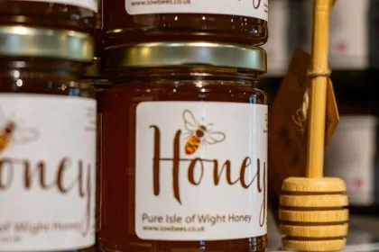 Jars of Isle of Wight honey with wooden honey dipper