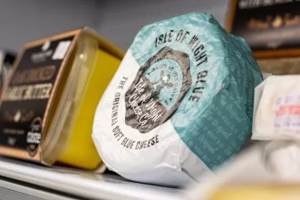 Wrapped blue cheese wheel on a shop shelf with other cheeses