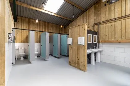 Modern glamping shower and toilet block with wooden walls, cubicles and sinks