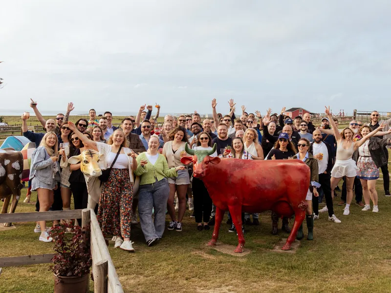 Large group celebrating outdoors at Tapnell Farm beside colourful cow sculptures