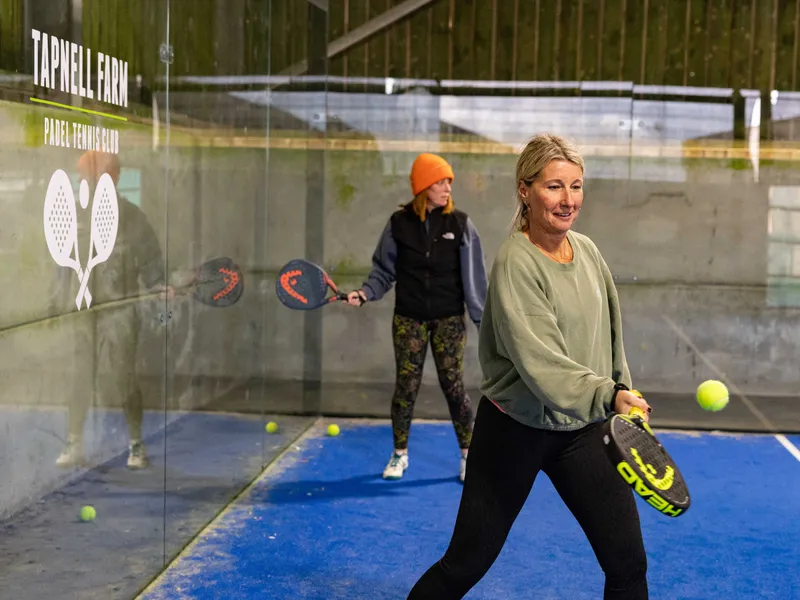 Two women playing padel on an indoor court at Tapnell Farm Padel Tennis Club