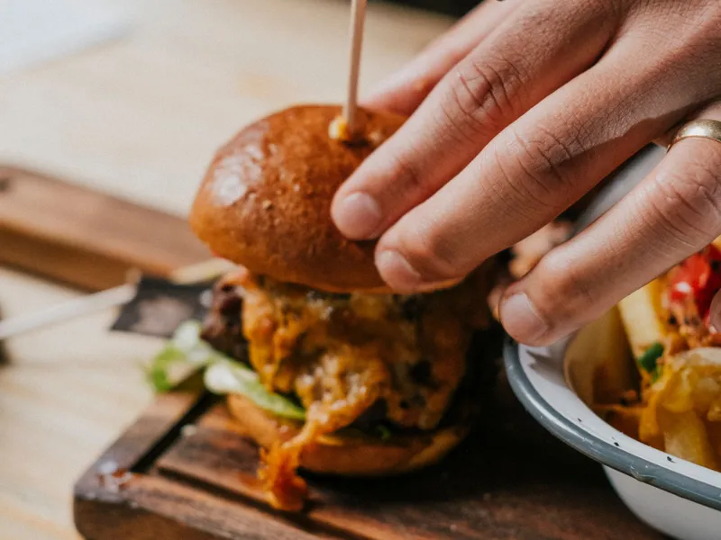 Hand holding a burger with a small flag reading 