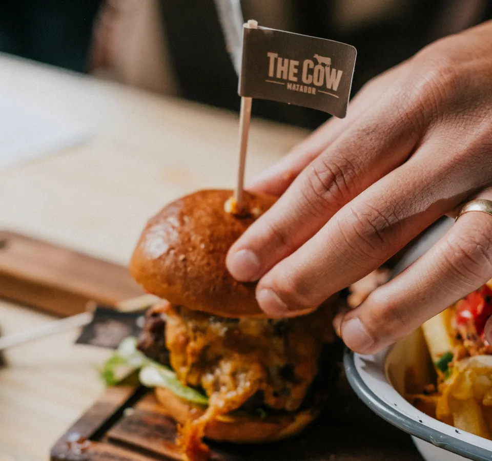 Hand holding a burger with a small flag reading 