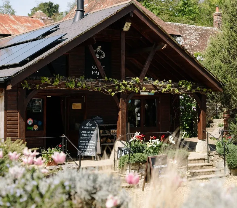 Entrance to The Garlic Farm restaurant and shop in a wooden building with solar panels and garden flowers