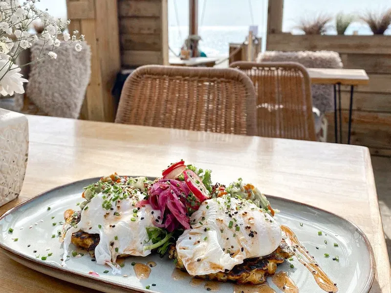 Poached eggs with herbs and pickled onions on a plate in a rustic seaside café