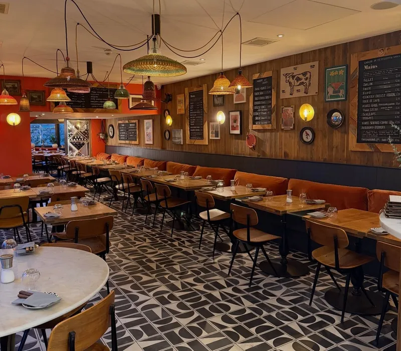 Cosy restaurant interior with wooden tables, patterned floor tiles and colourful woven pendant lights