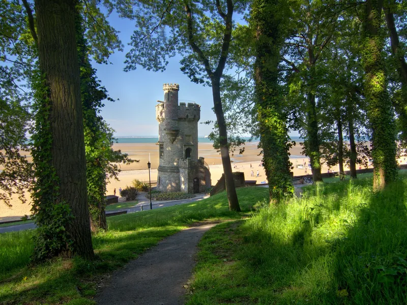 Appley Tower framed by leafy trees overlooking the sandy beach and sea