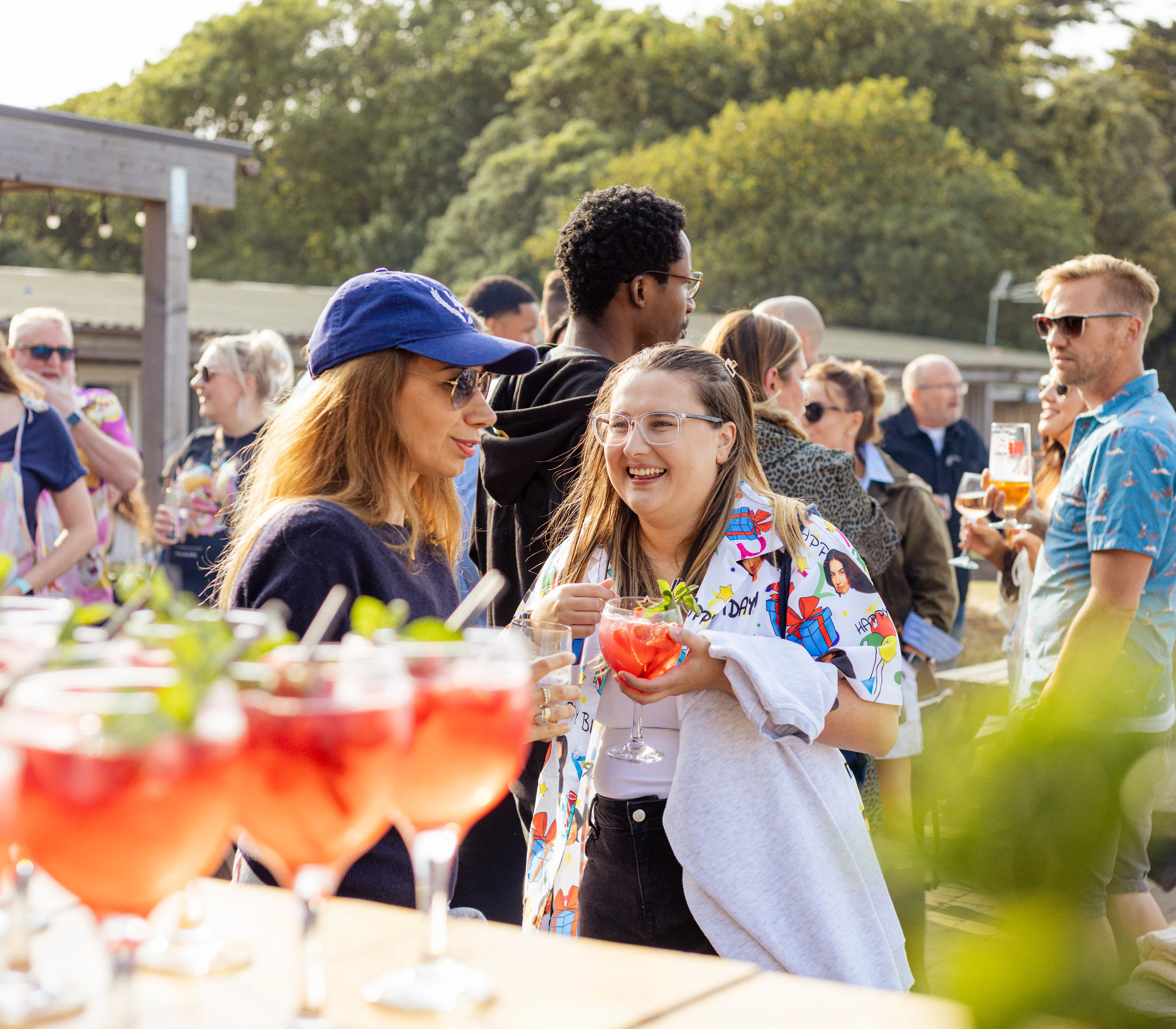 People chatting at an outdoor corporate event with cocktails on a sunny day