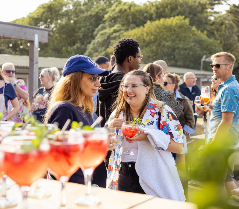 People chatting at an outdoor corporate event with cocktails on a sunny day