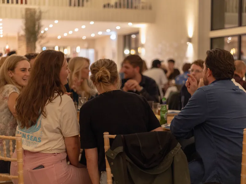 Group of colleagues chatting at a long table during an indoor corporate dinner