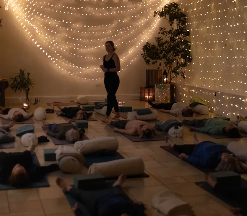 Yoga nidra session with participants resting on mats beneath warm fairy lights at East Afton Farmhouse