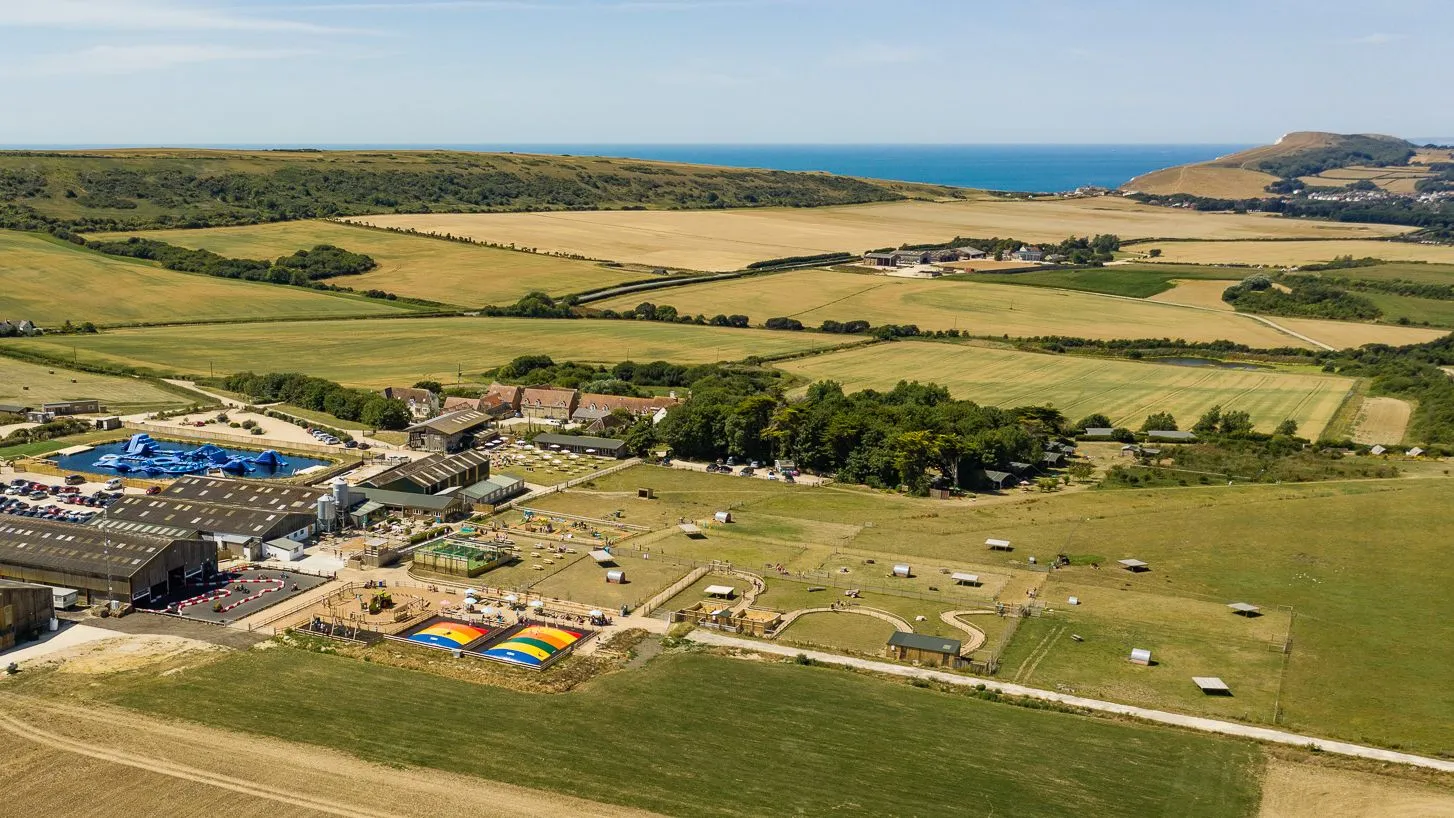 Aerial view of Tapnell Farm park with barns, outdoor attractions and fields leading to the coastline