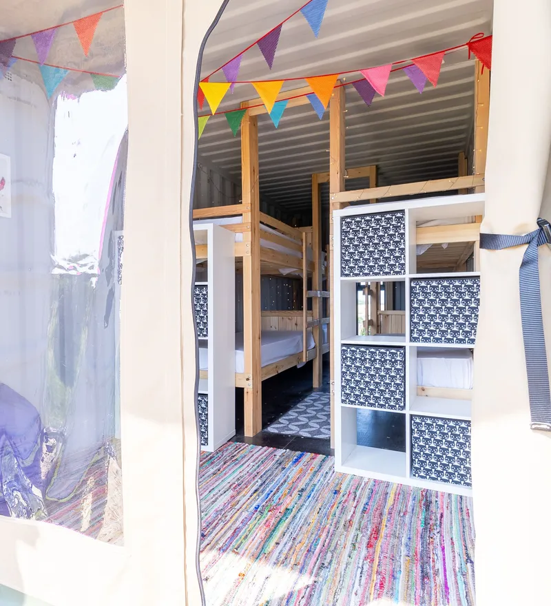 Entrance to a cosy bunk room with wooden bunk beds, colourful bunting and patterned storage cubes