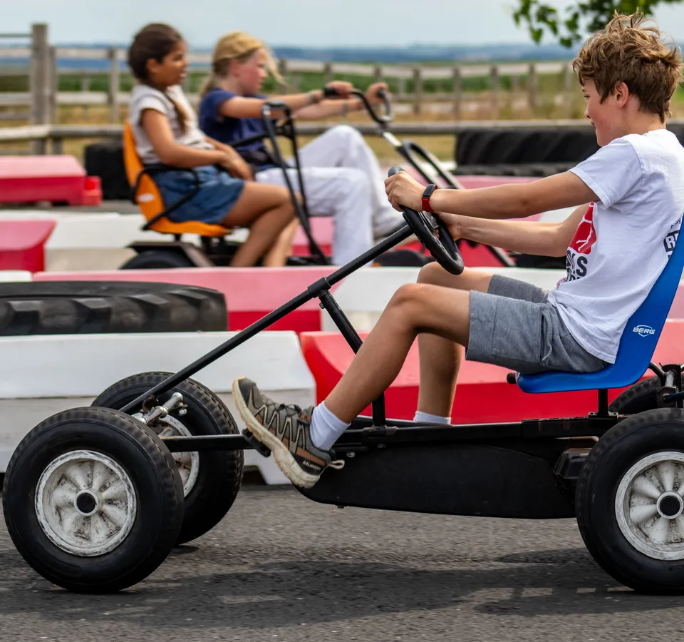 Children riding pedal go-karts on an outdoor track at Tapnell Farm Park