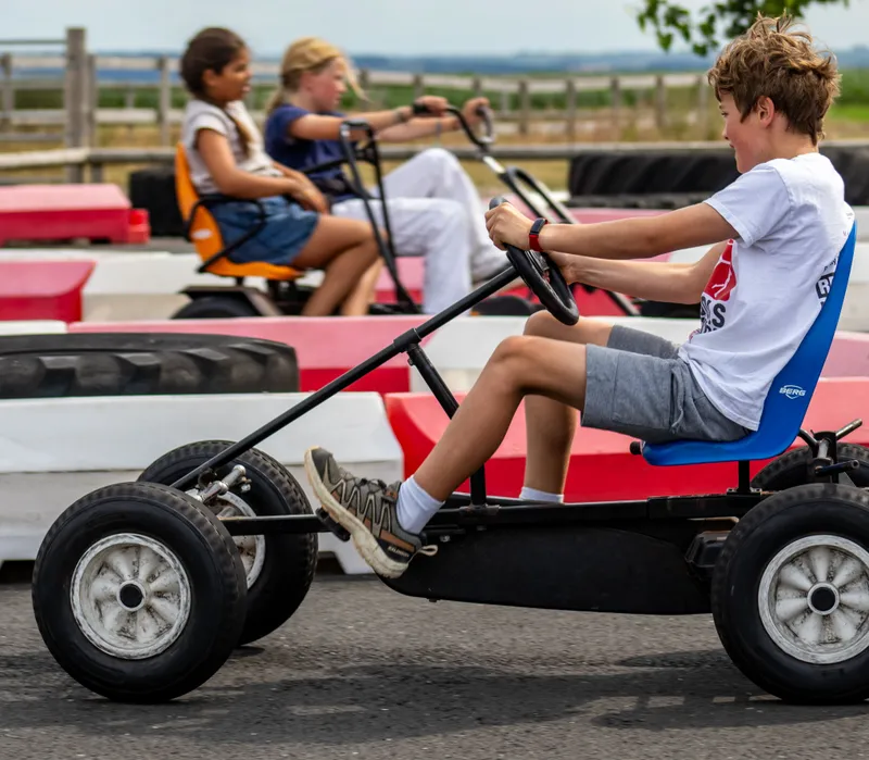 Children riding pedal go-karts on an outdoor track at Tapnell Farm Park