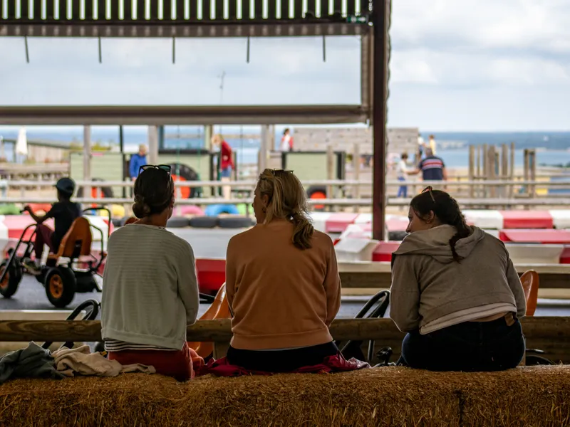 People sitting on hay bales watching a go-kart track at Tapnell Farm Park