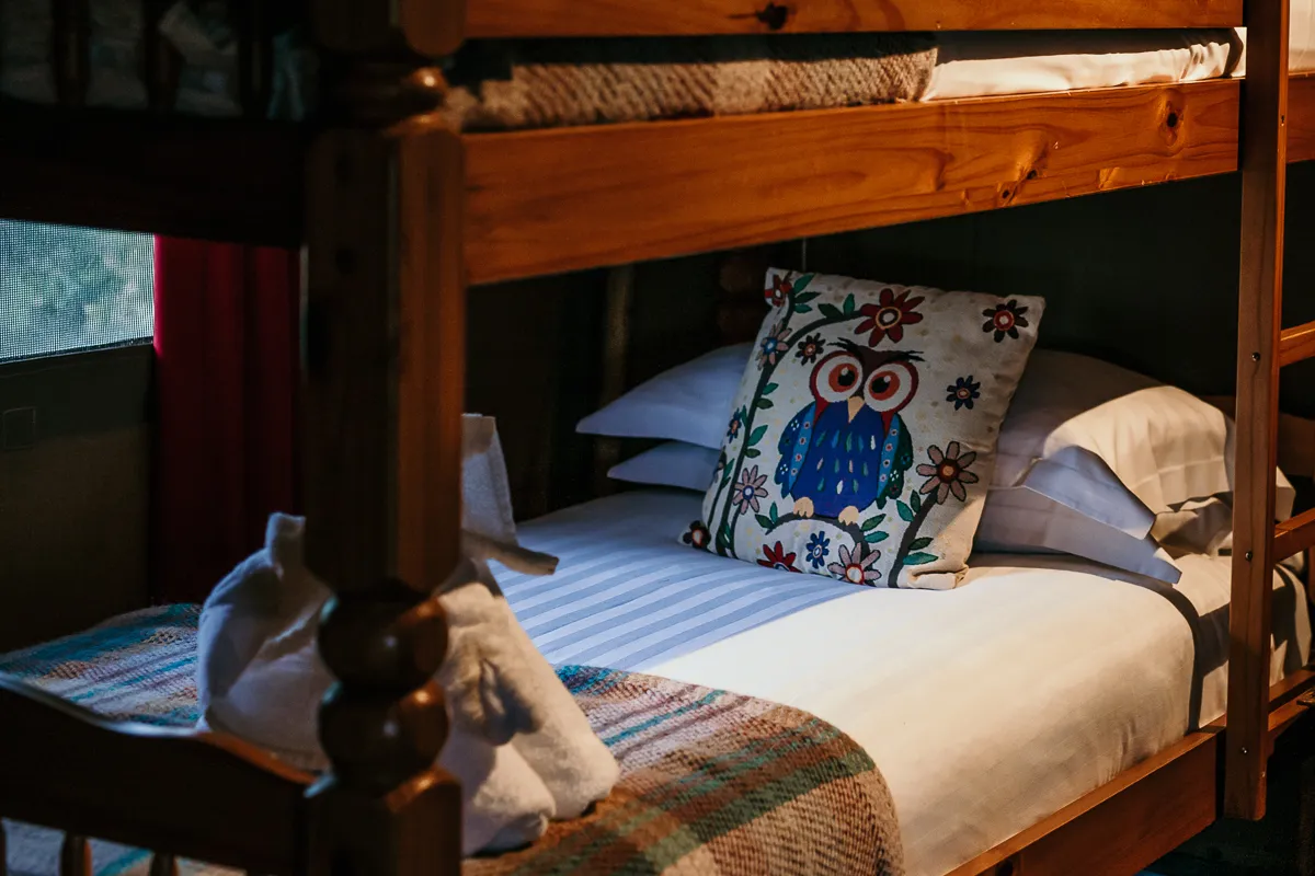 Lower bunk bed with owl cushion and striped bedding in a cosy room