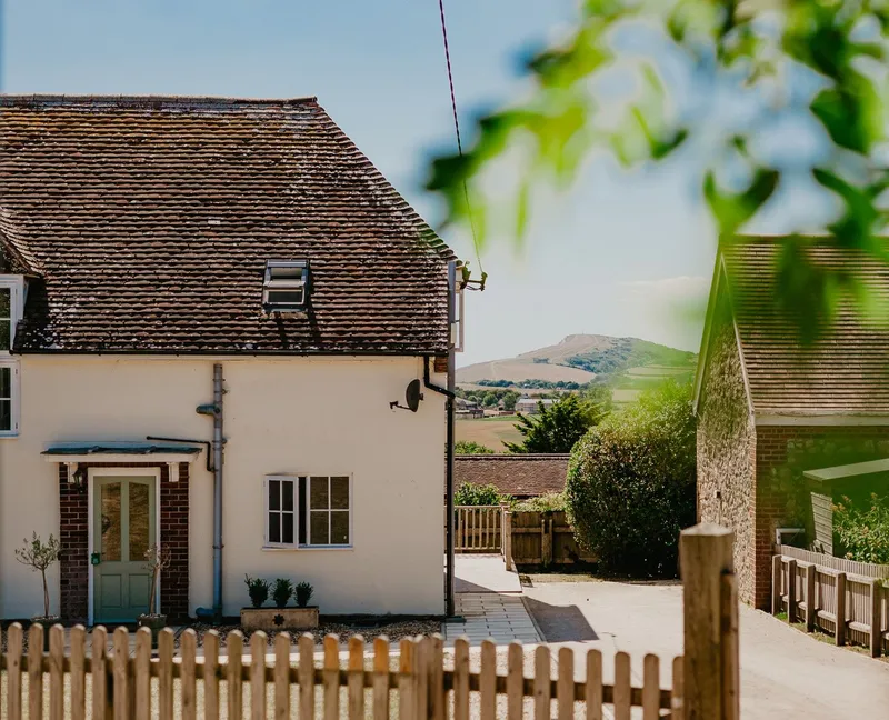 Exterior of Tapnell Farm Dairyman’s Cottage with a picket fence and countryside views