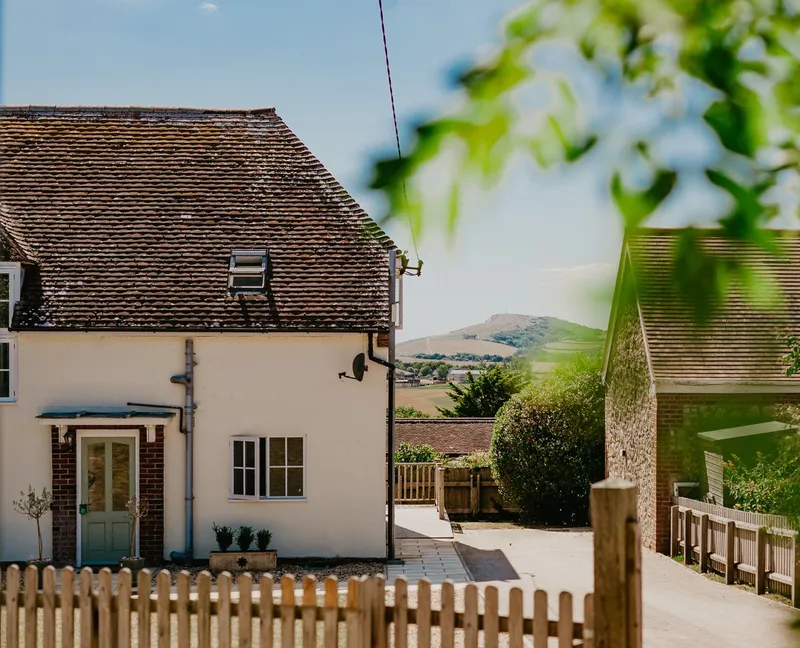 Exterior of Tapnell Farm Dairyman’s Cottage with a picket fence and countryside views