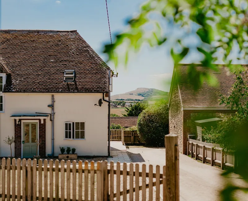 Exterior of Tapnell Farm Dairyman’s Cottage with a picket fence and countryside views