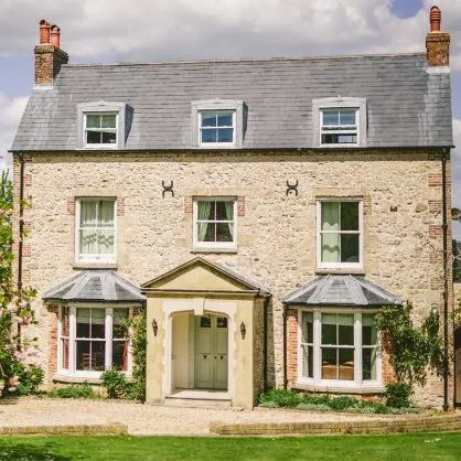 Stone country house with slate roof and bay windows beside a blooming pink tree