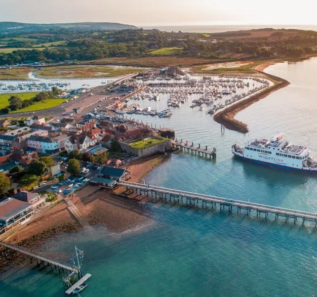 Aerial view of Yarmouth harbour with marina, pier and a ferry entering the harbour at sunset