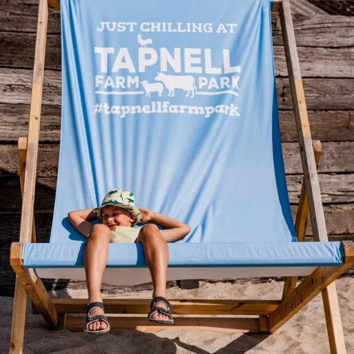 Child relaxing on a blue deckchair at Tapnell Farm Park