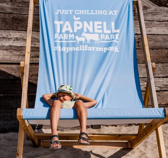 Child relaxing on a blue deckchair at Tapnell Farm Park