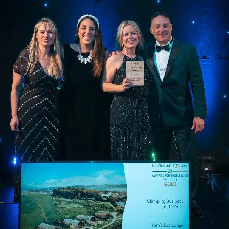 Four people on stage holding a Gold award for Glamping Business of the Year at the Beautiful South Awards for Excellence 2024–2025.