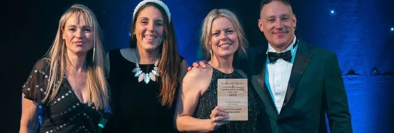 Four people on stage holding a Gold award for Glamping Business of the Year at the Beautiful South Awards for Excellence 2024–2025.
