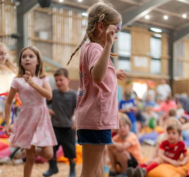Children dancing at an indoor kids’ party with colourful beanbags and balloons in the background