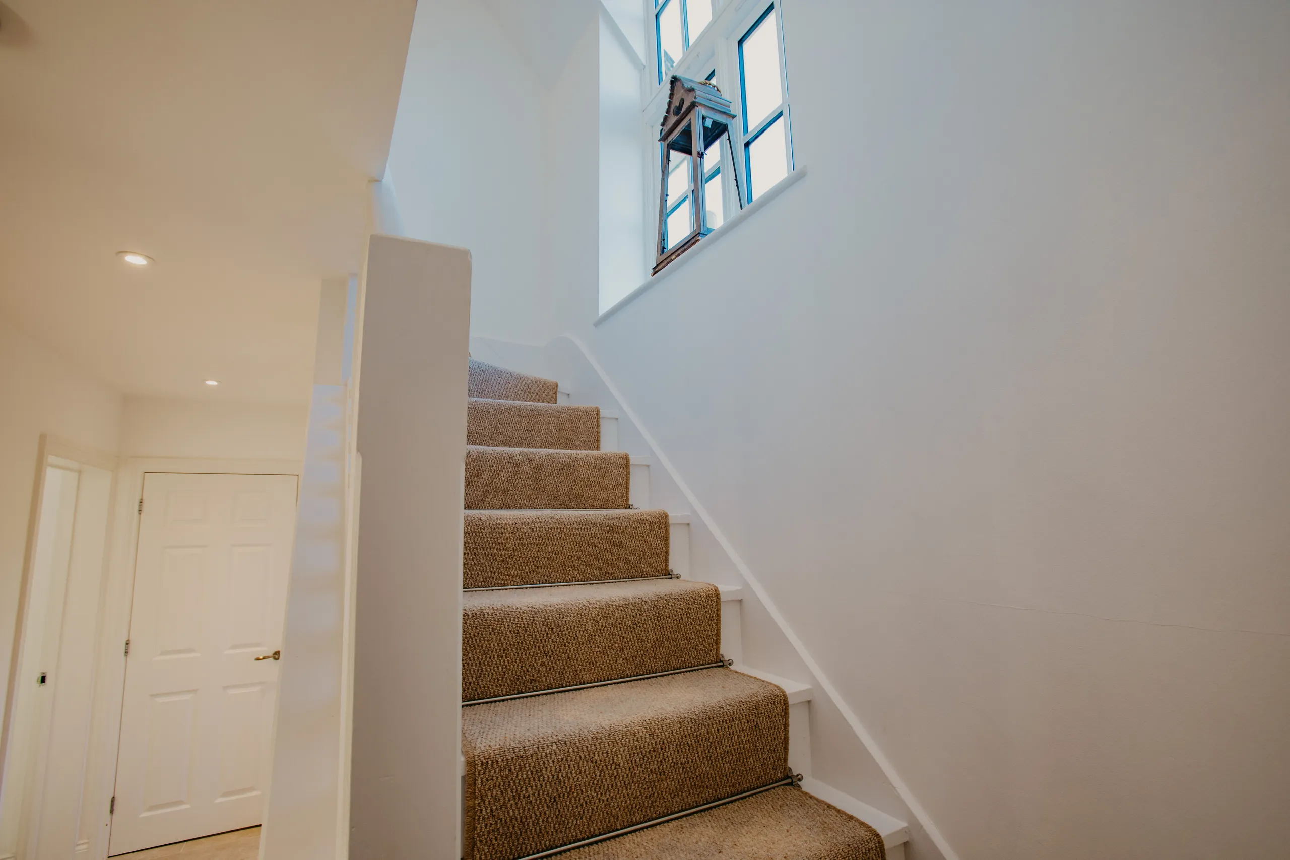 Carpeted staircase with white walls and a tall window in Dairyman's Cottage