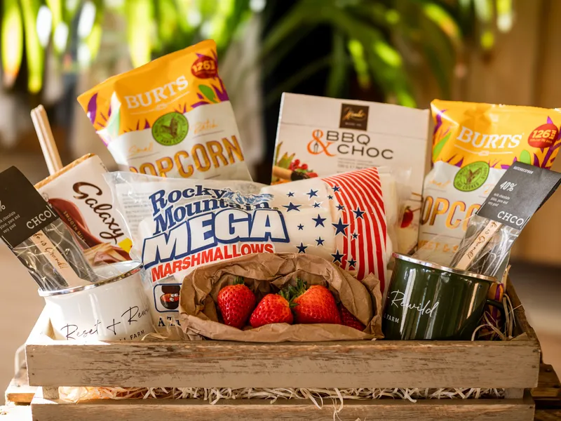 Gift hamper with popcorn, marshmallows, chocolate and fresh strawberries in a wooden crate