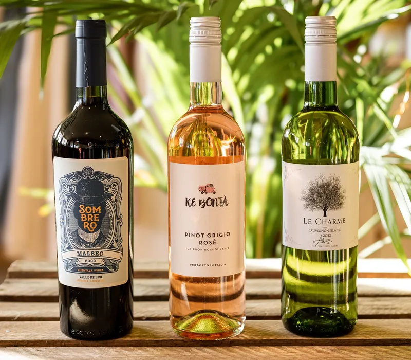 Three bottles of wine on a wooden crate with green foliage in the background