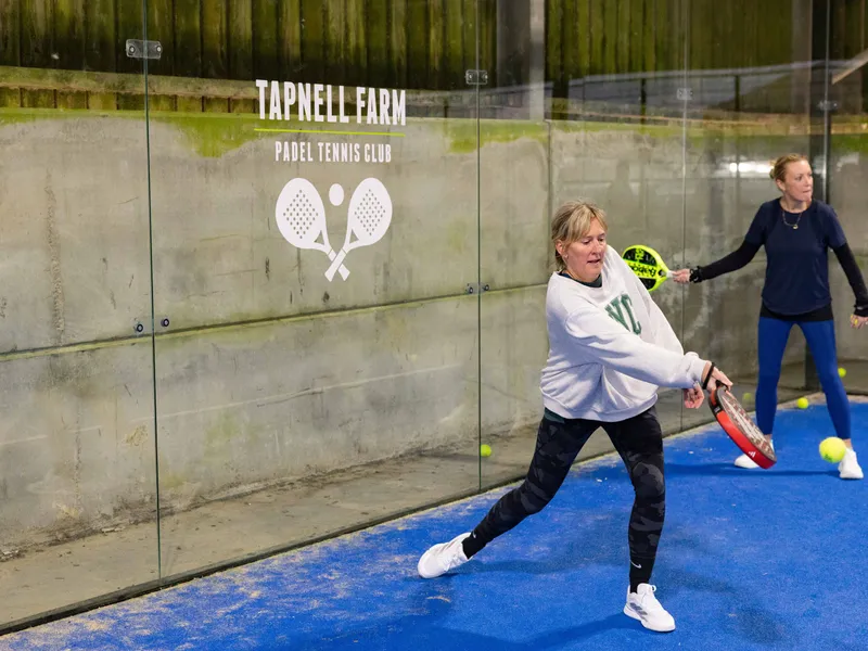 Two women playing padel on an indoor court at Tapnell Farm Padel Tennis Club
