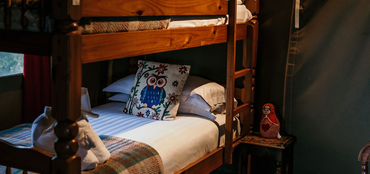 Wooden bunk beds with owl cushions in a cosy tent bedroom