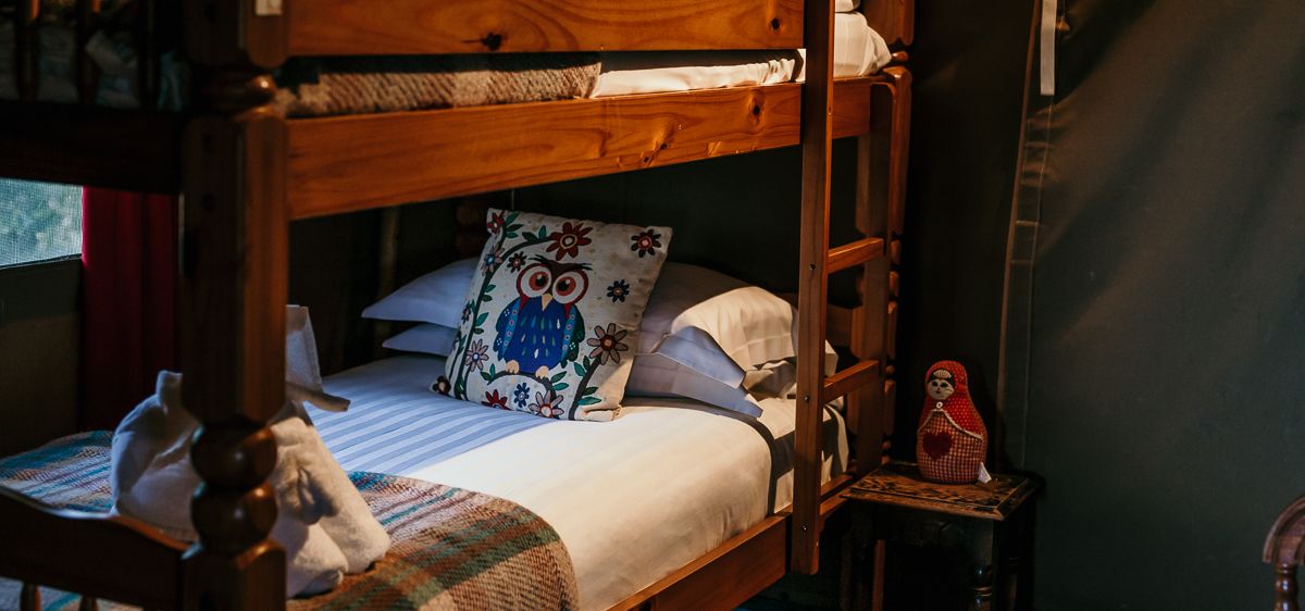 Wooden bunk beds with owl cushions in a cosy tent bedroom