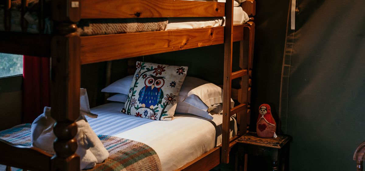 Wooden bunk beds with owl cushions in a cosy tent bedroom