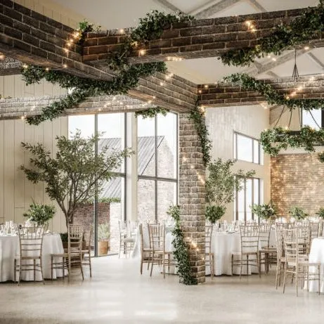 Rustic barn-style event space with brick beams, fairy lights and round tables set for a reception