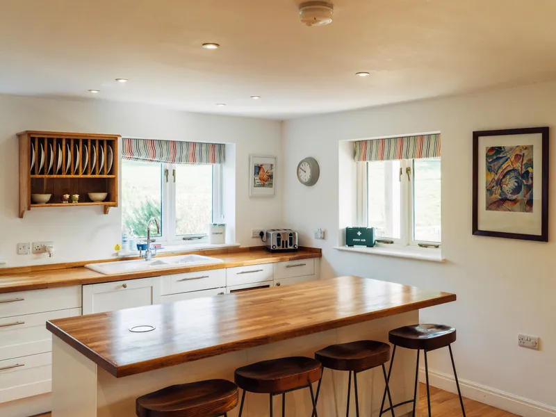 Bright country kitchen with wooden worktops, breakfast bar and striped Roman blinds