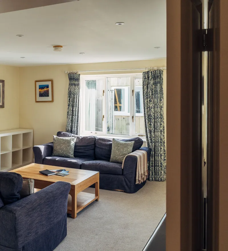 Cosy living room with blue sofas, patterned curtains and a wooden coffee table