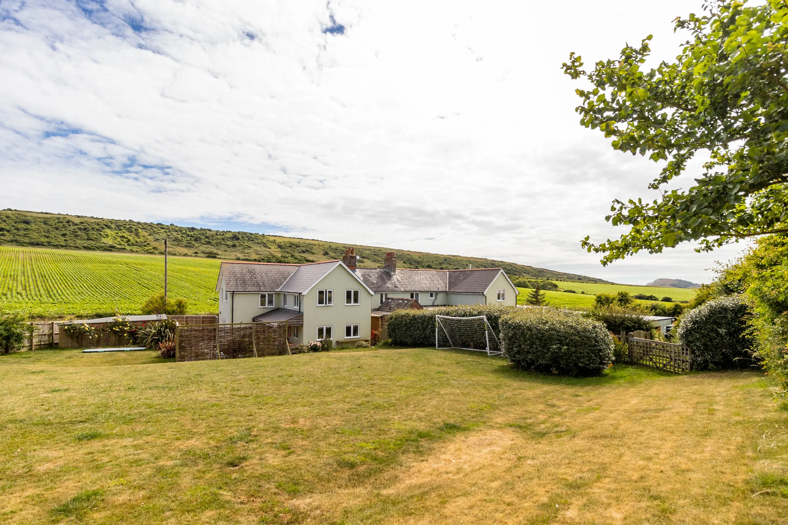 Exterior of Poachers Lodge at Tapnell Farm with a large garden, surrounding fields and countryside views