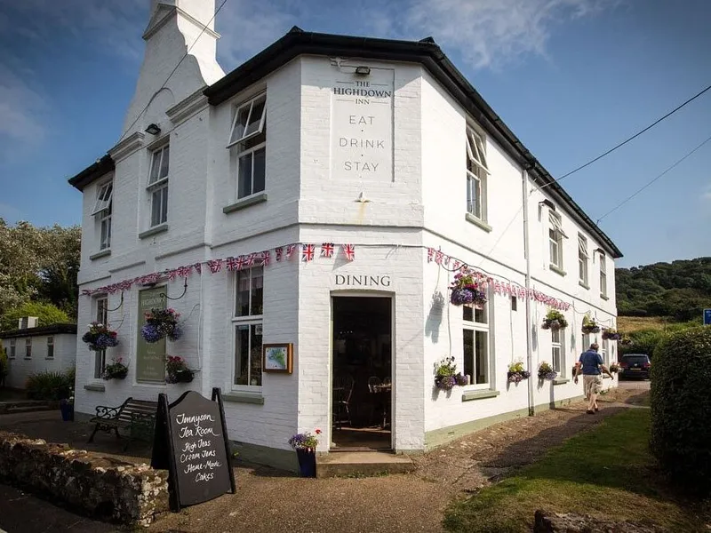 Exterior of The Highdown Inn, a white countryside pub and inn with hanging baskets and bunting