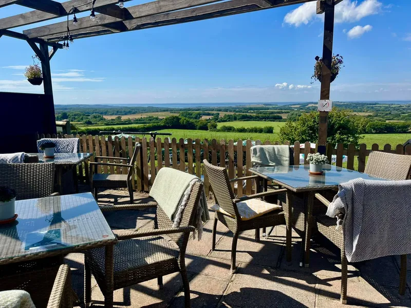 Outdoor seating area at Blacksmiths with countryside views under a wooden pergola