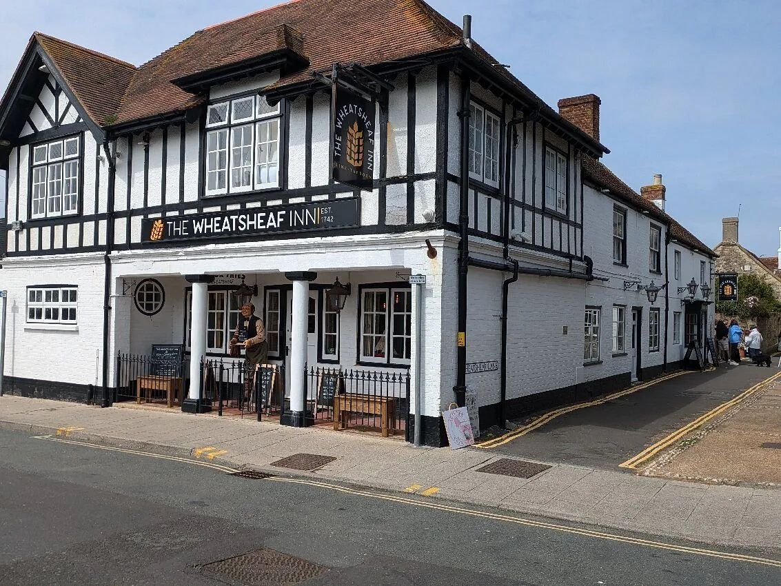 Exterior view of The Wheatsheaf Inn, a traditional black-and-white timber-framed pub on a street corner.