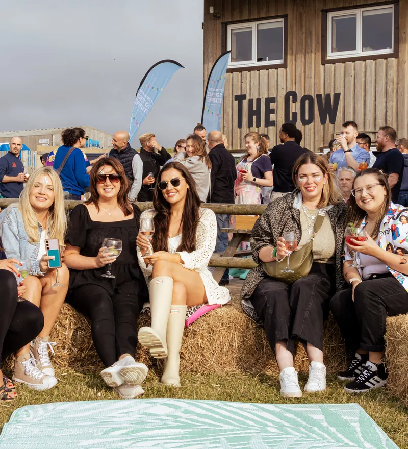 Guests relaxing on hay bales outside The Cow at Tapnell Farm during a corporate event