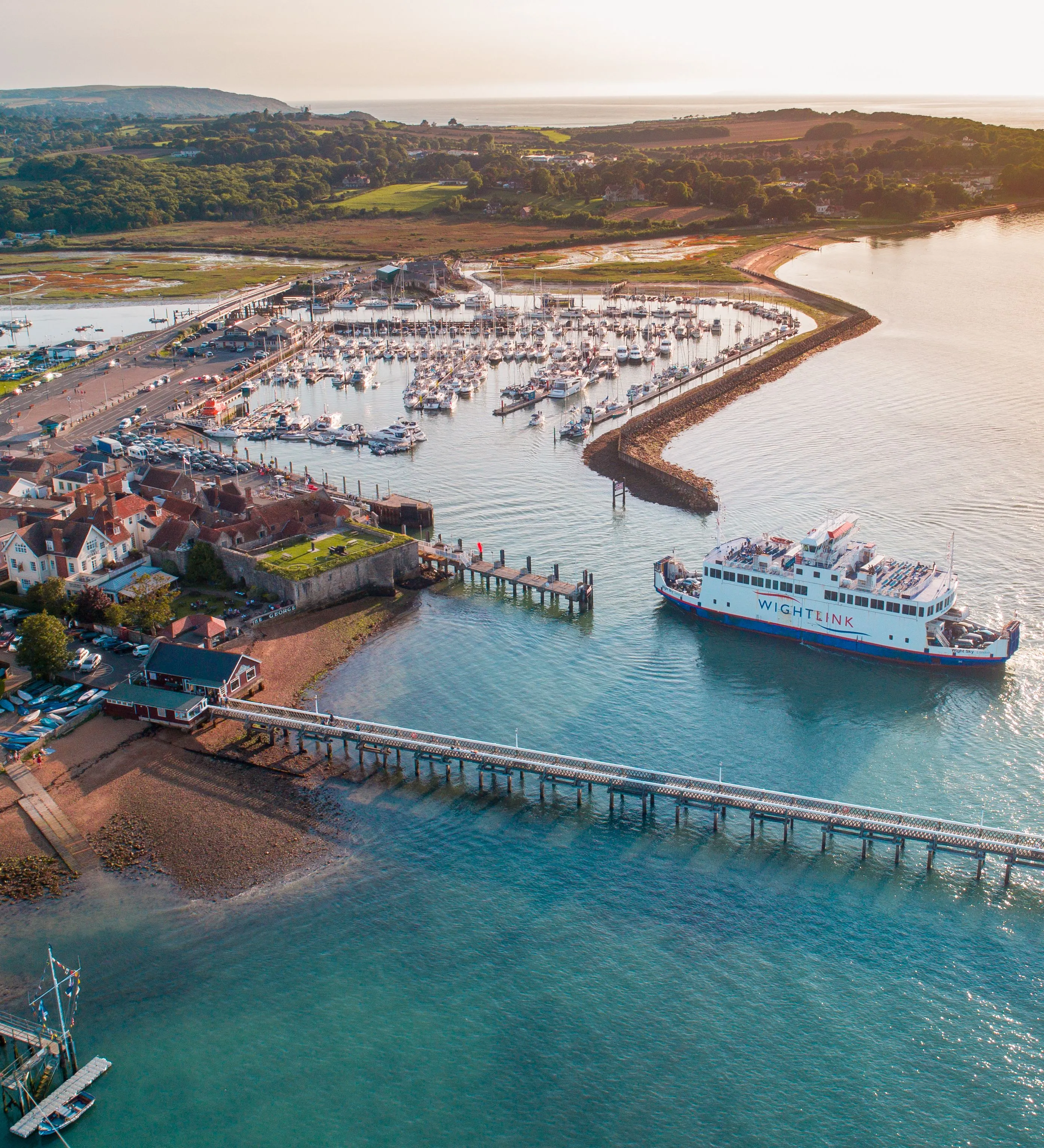 Aerial view of Yarmouth harbour with a Wightlink ferry, marina, pier and surrounding countryside on the Isle of Wight.