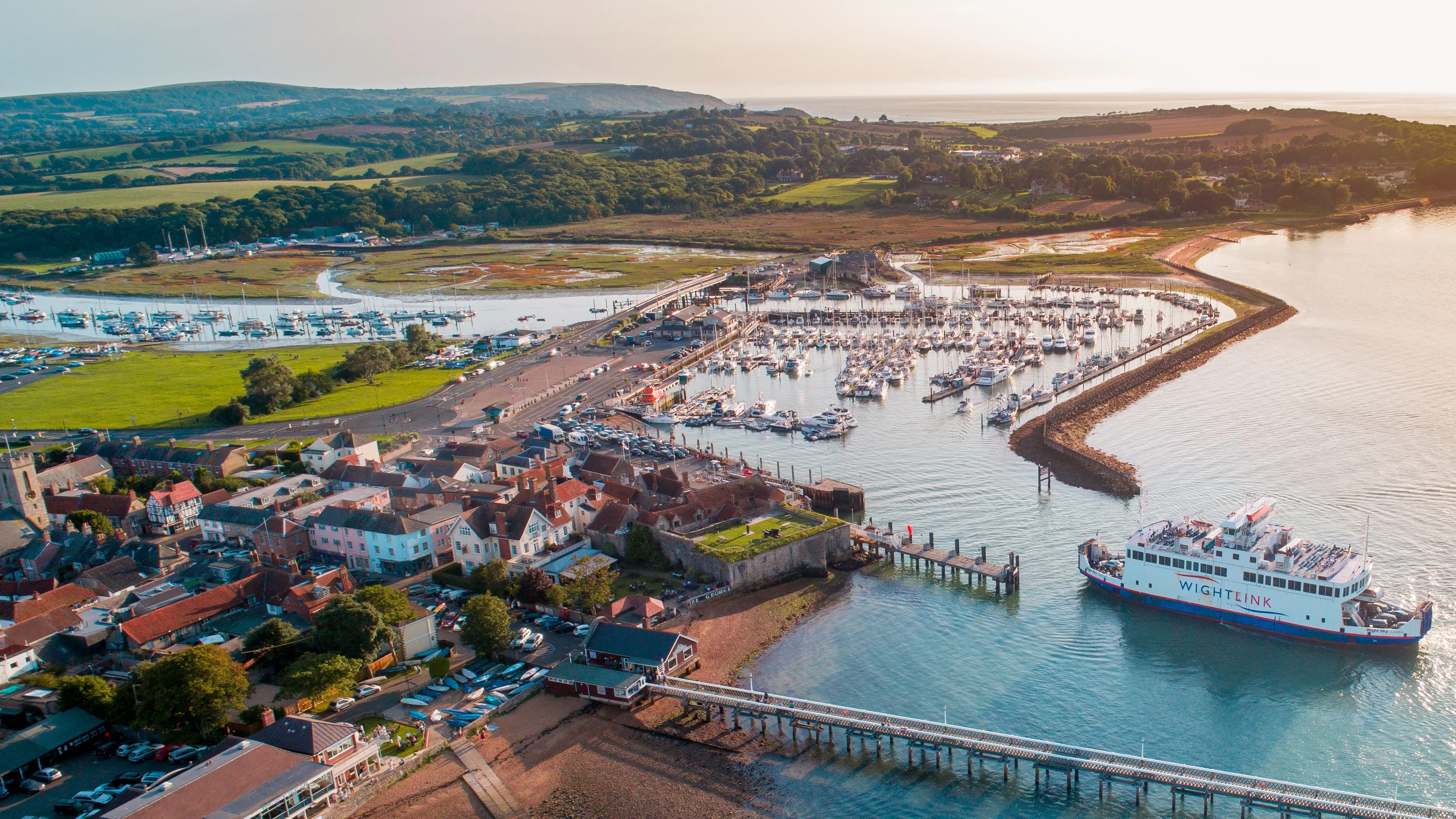 Aerial view of Yarmouth harbour with a Wightlink ferry, marina, pier and surrounding countryside on the Isle of Wight.