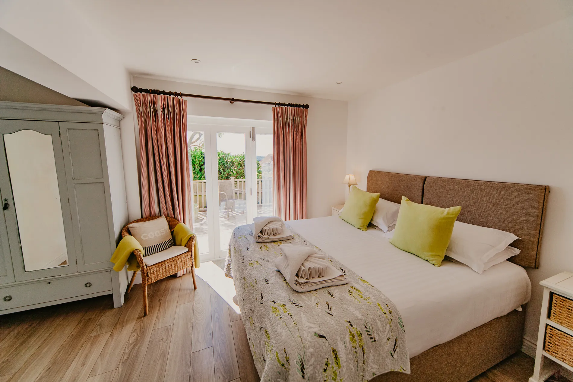 Cosy ground-floor bedroom with double bed, green cushions and French doors to a terrace at Dairyman's Cottage, Tapnell Farm